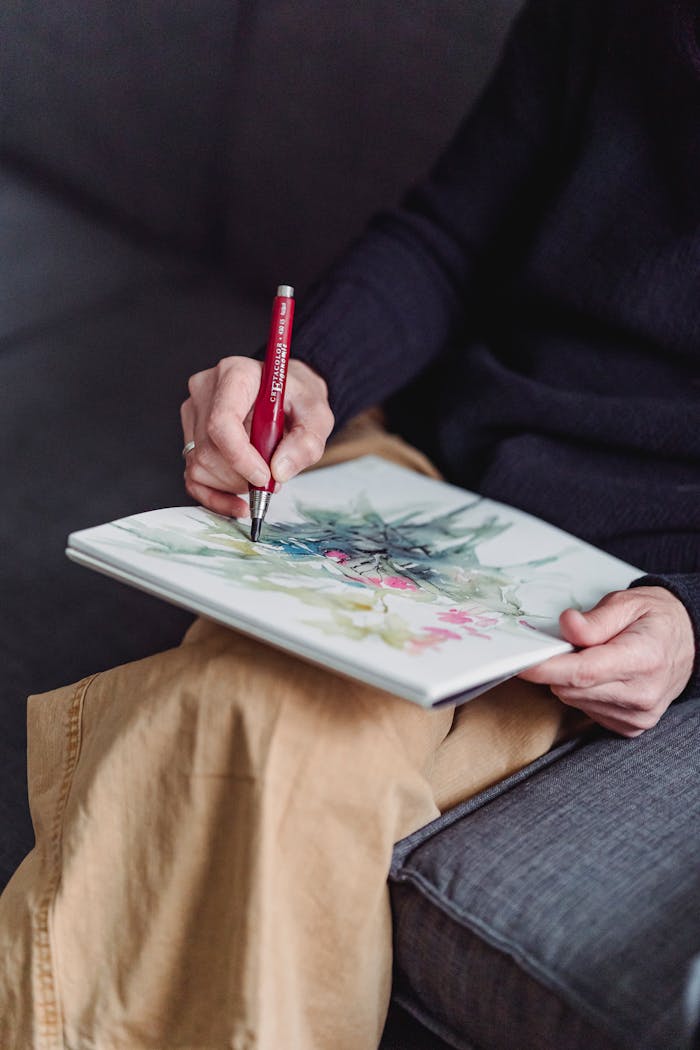 Close-up of an artist sketching colorful artwork in a cozy indoor setting.